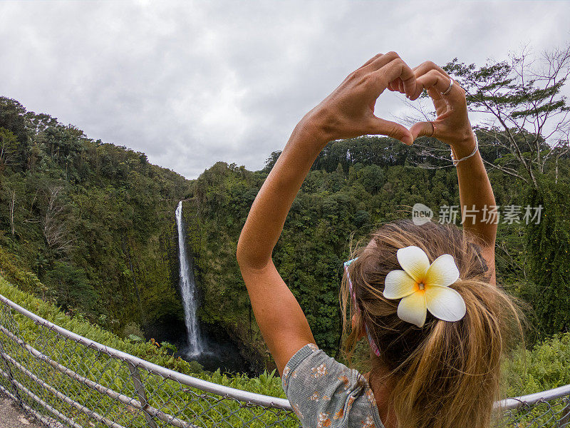 在夏威夷瀑布上做心形图案的女人