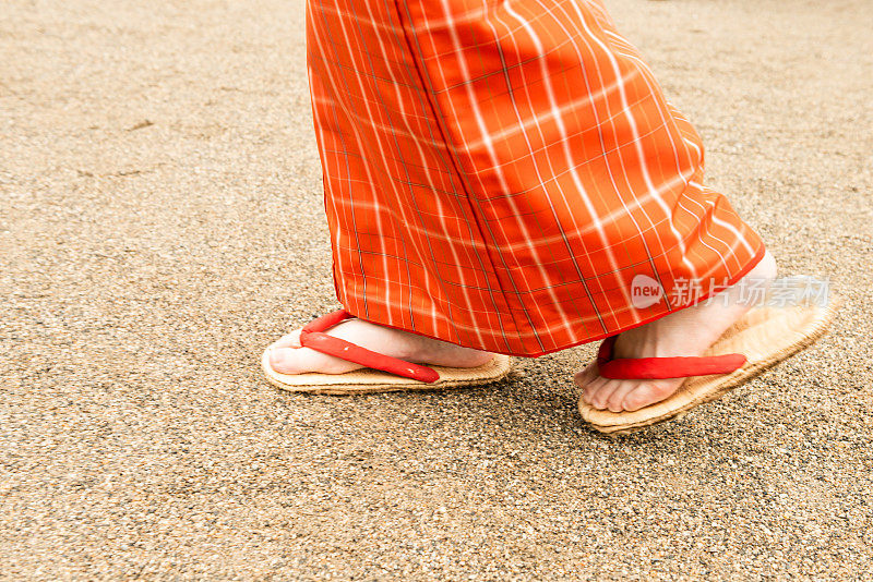 一个日本女人的脚走在一条土路上