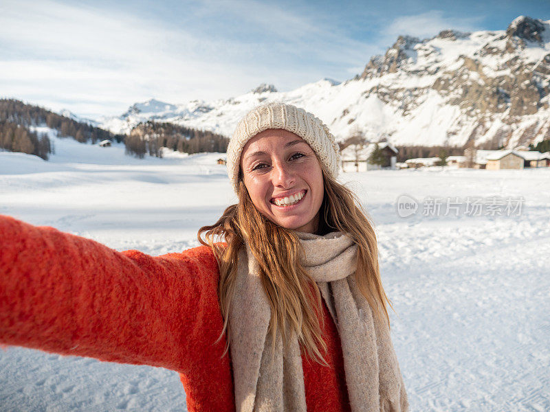 年轻女子在冬天与雪山景观自拍;人们在寒假里玩得很开心