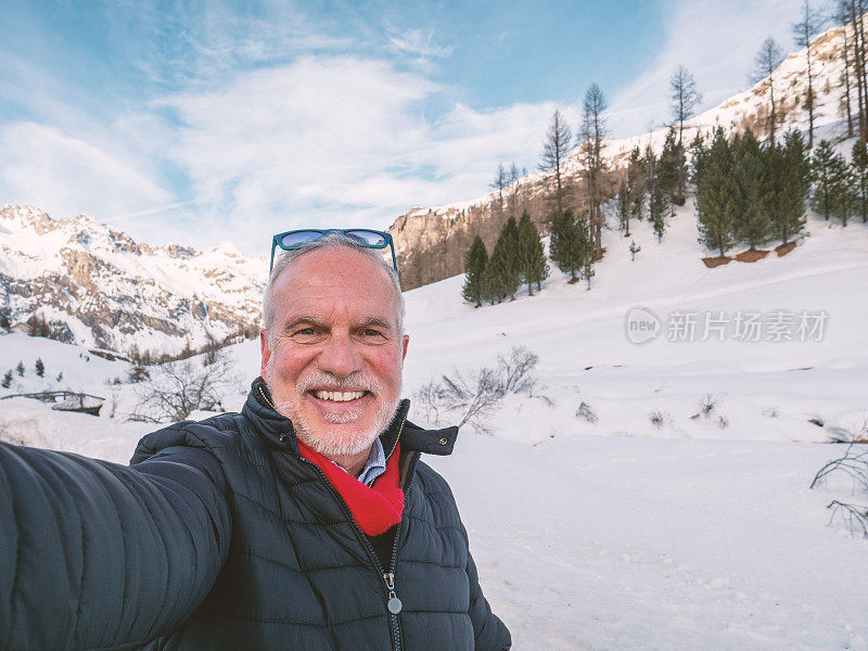 成熟的男人在冬天与雪山景自拍;人们在寒假里玩得很开心