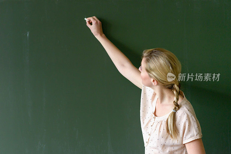 女教师用粉笔在黑板上写字