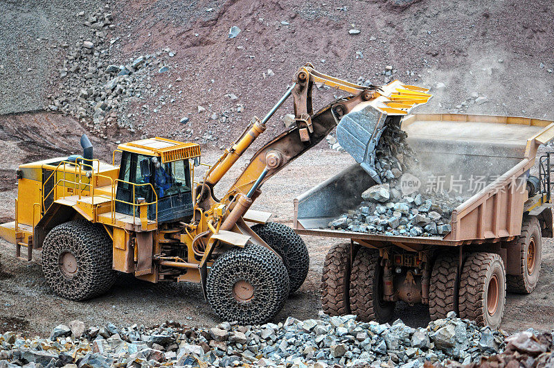 在露天矿山装卸车装载岩石材料的推土机。的猎物。