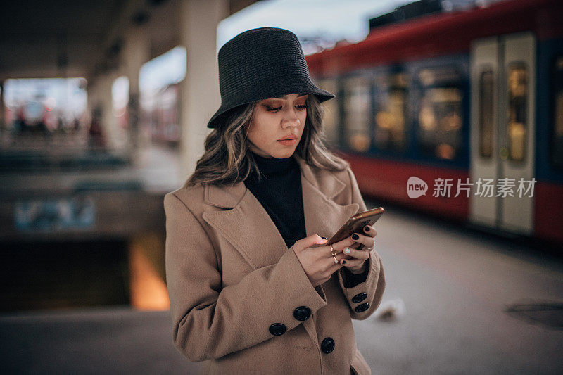 一名年轻女子在火车站使用手机