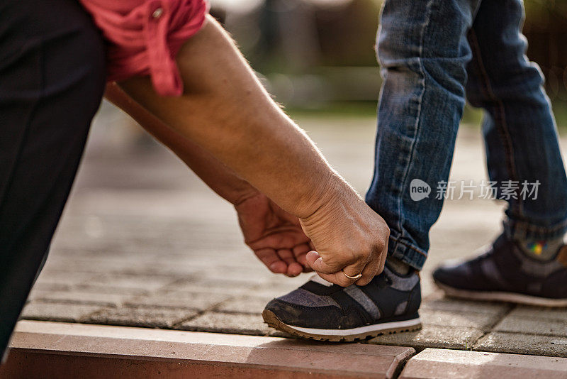 靠近系鞋带的女人在男孩的鞋子上