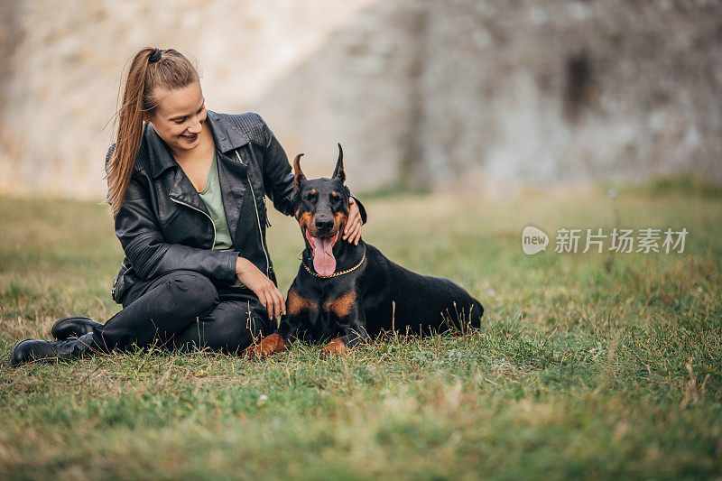 一个女人在公园里和她的杜宾犬玩耍