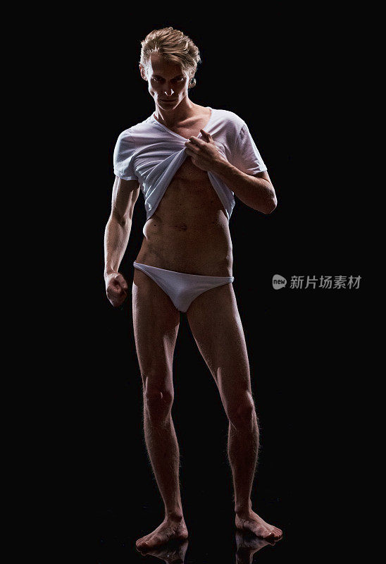 白人年轻男性脱衣舞娘前面的黑色背景穿着衬衫