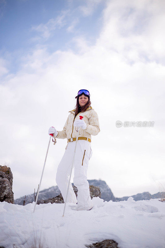 近景美丽的年轻女子在冬天的衣服站在一边，手拿木棍的背景雪山