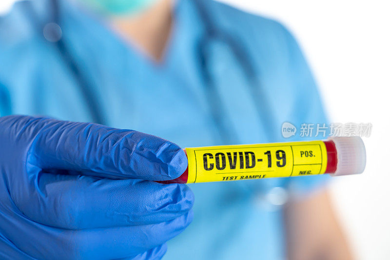 年轻男医生手持手术手套和防护口罩，手持COVID-19(冠状病毒)血液检测样管，背景白色