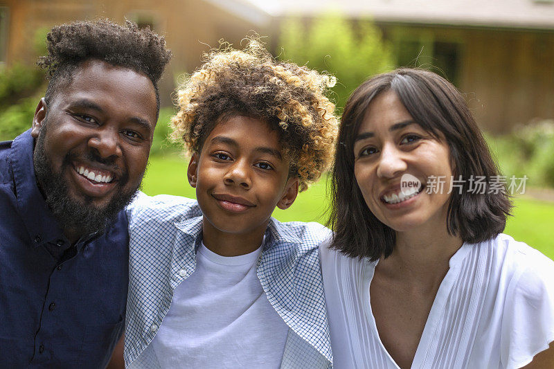 一个快乐的多元文化家庭与一个儿子在度假别墅后院拥抱的肖像