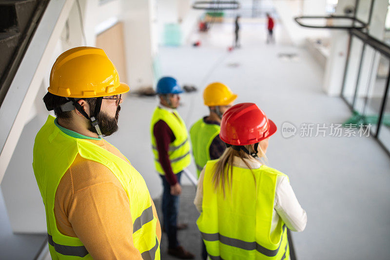 建筑工程师走下楼梯，在即将完工的建筑内谈论工作进度