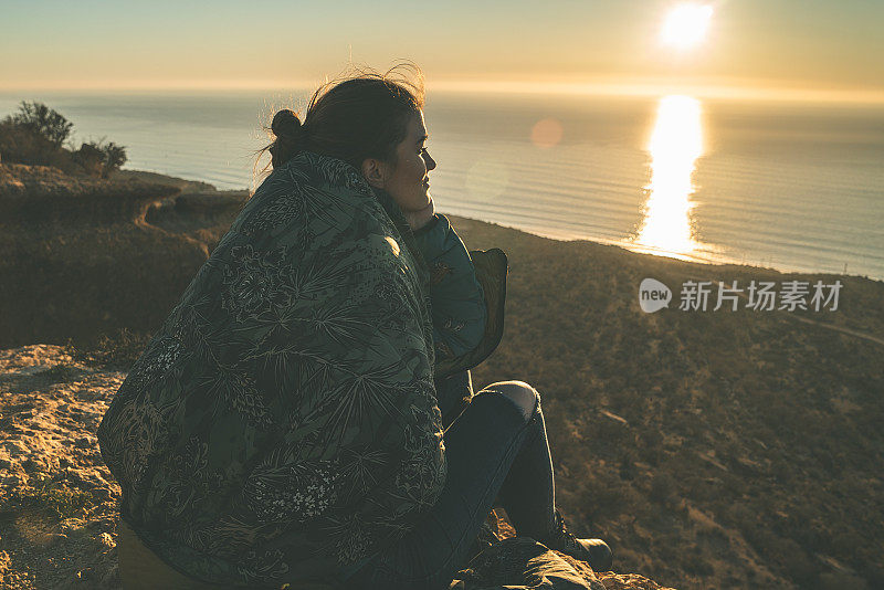 海景和山脉。一个女人在悬崖边欣赏史诗般的日落