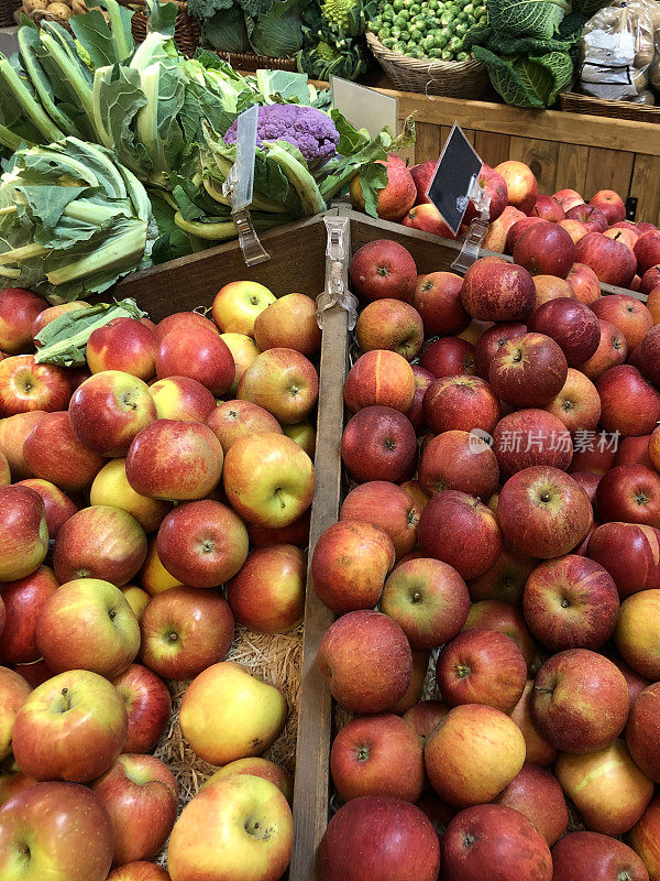 农家商店展示的新鲜水果和蔬菜，包括苹果，卷心菜，球芽甘蓝，花椰菜和土豆，集中在前景