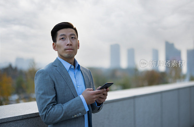 年轻的中国商人在户外使用手机