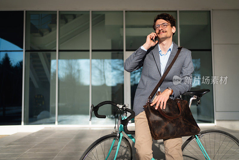 微笑着靠在自行车上打电话的商人