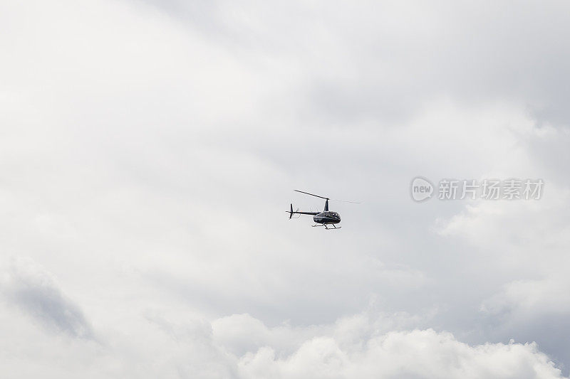 享受直升飞机在蓝色的旅游飞行在天空与云。有可能发生灾难的恶劣天气。