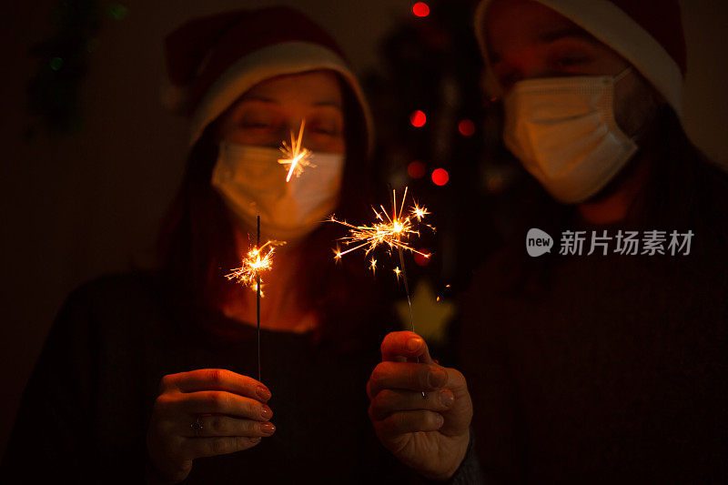 幸福的家庭在医疗面具和烟花庆祝圣诞节或新年。