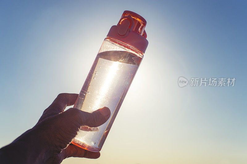 一个人在阳光下举着一个可重复使用的水瓶。