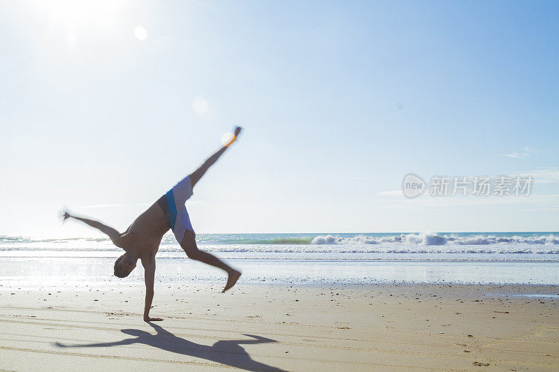 在海滩上做瑜伽和杂技体操的男子体操运动员