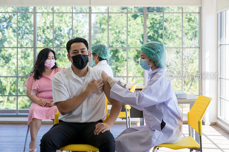 一名医生使用注射器为亚洲人民注射新冠肺炎疫苗，预防新冠肺炎疫情的爆发