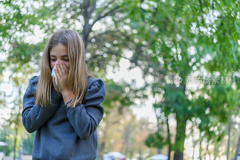 感冒和高烧的生病女孩在户外打喷嚏和咳嗽。