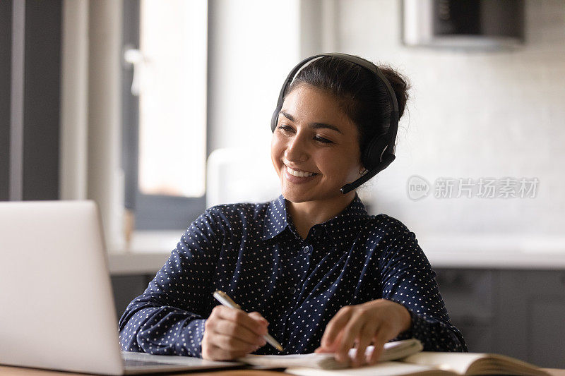 微笑的印度妇女戴着耳机参与在线课程