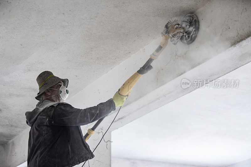 建筑工人正在用砂纸打磨墙壁