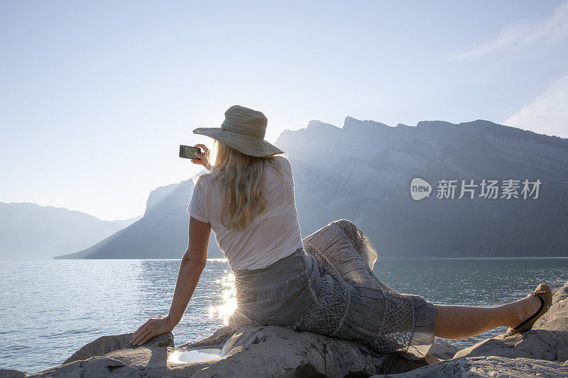 女人在山湖边休息，拍照