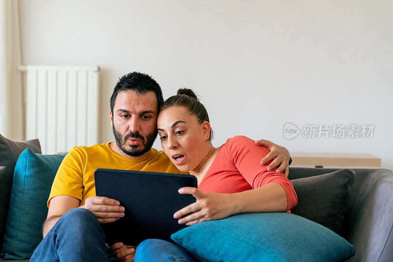 一对年轻夫妇在客厅看平板电脑