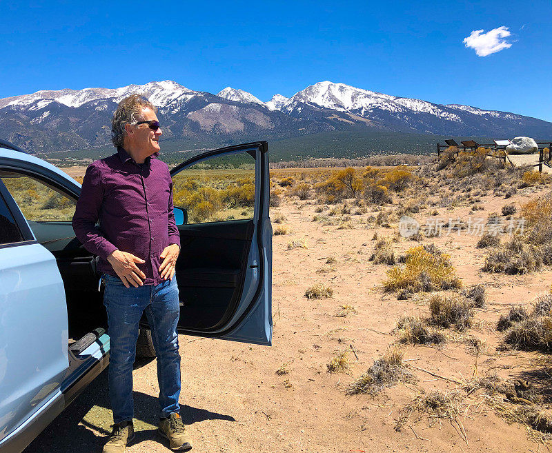 科罗拉多公路之旅:男人靠近汽车，雪山背景