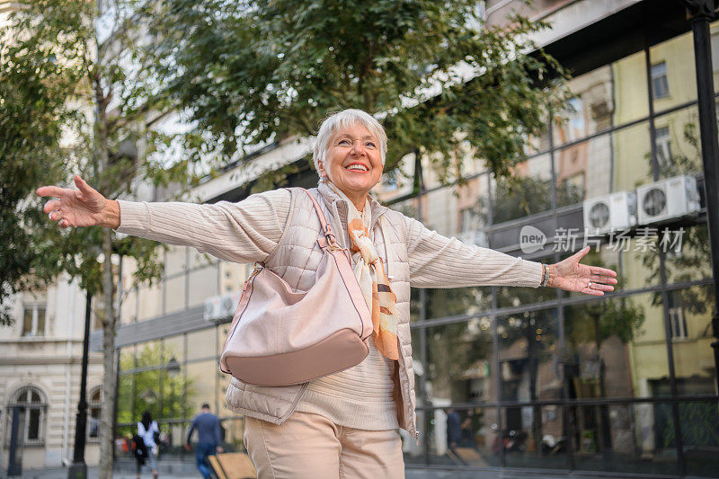 一位老年妇女在城市散步度过美好的一天。