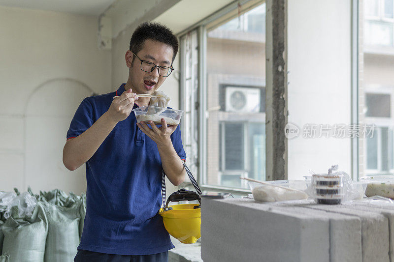 亚洲男工程师在装修工地吃外卖