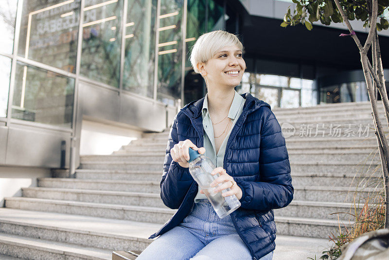 一个女孩的肖像在街上享受和她的可重复使用的水瓶