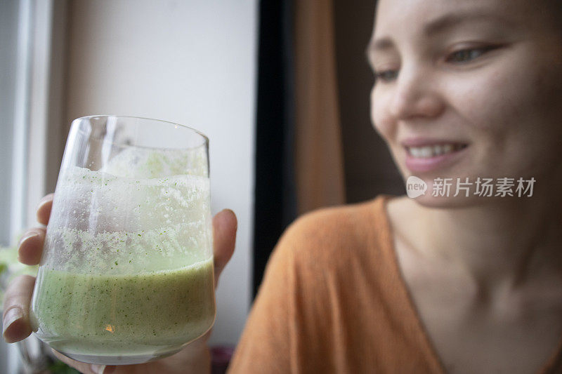 年轻女子在家喝绿色果汁