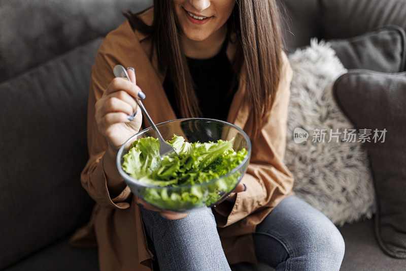 健康的女性在家里吃新鲜的有机沙拉当午餐