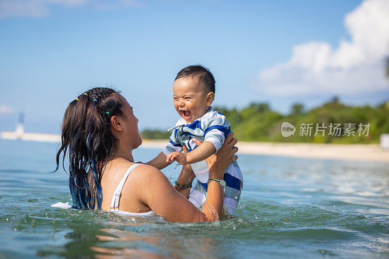 妈妈和儿子在海滩上玩得很开心。