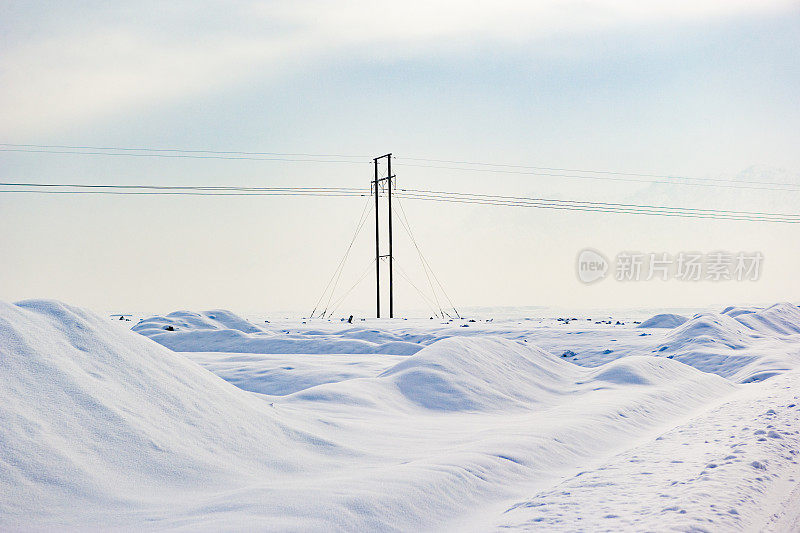 中国新疆阿克苏县农村地区积雪路面上的电塔