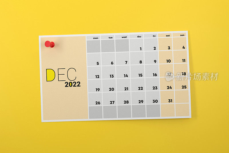 2022年12月日历页钉在黄色背景上