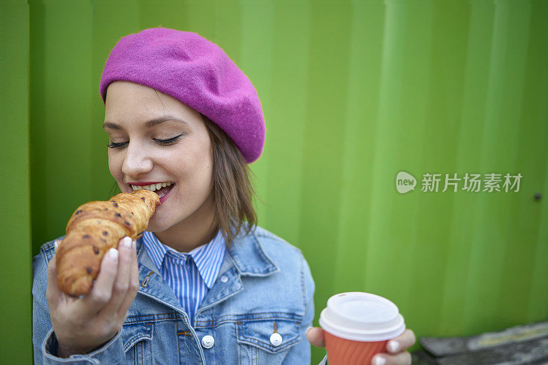 女人咬牛角面包户外酒吧早餐