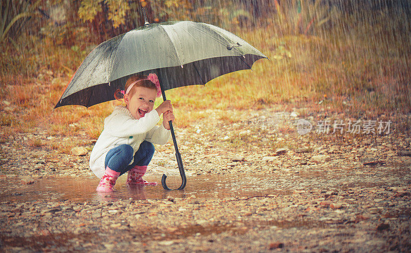 快乐的小女孩撑着伞在雨中洒落大自然