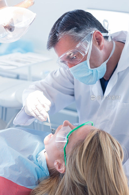 牙医在牙医的椅子上检查病人的牙齿