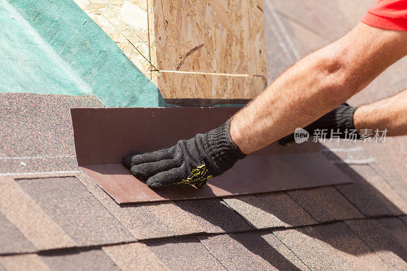 屋顶建筑工正在一个新的木屋顶上安装瓦片