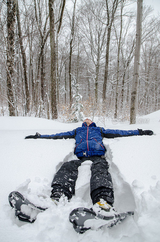 穿着雪鞋的女人躺在洁白的雪地里