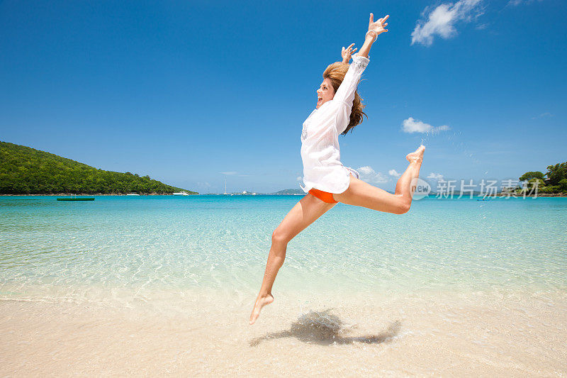 兴奋的女人跳跃的热带海滩上的喜悦