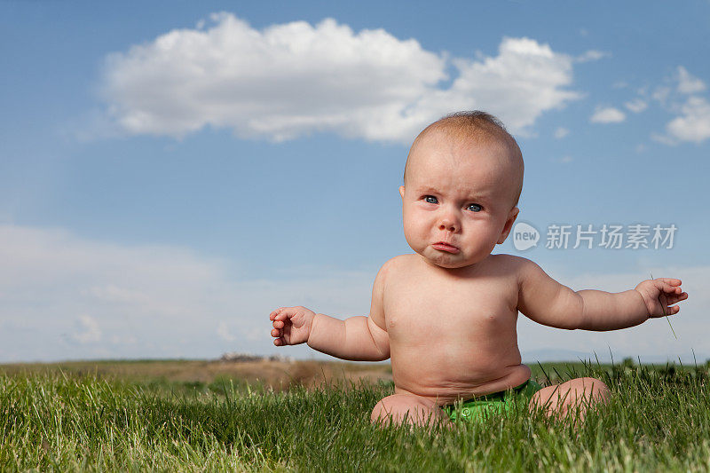 悲伤哭泣的婴儿坐在户外草地上