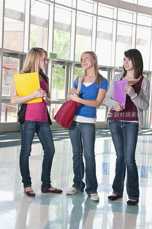 三个十几岁的女孩在高中走廊聊天