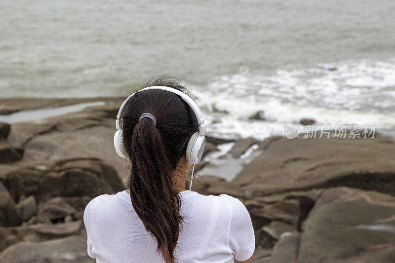 女孩戴着耳机，面朝大海