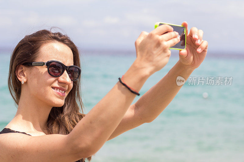 海滩上一个开心女人拿着手机的照片
