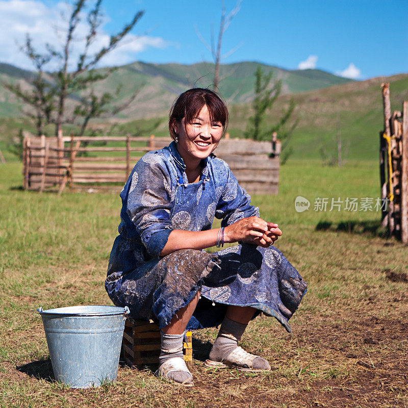 穿着民族服装、正在挤牦牛奶的蒙古妇女