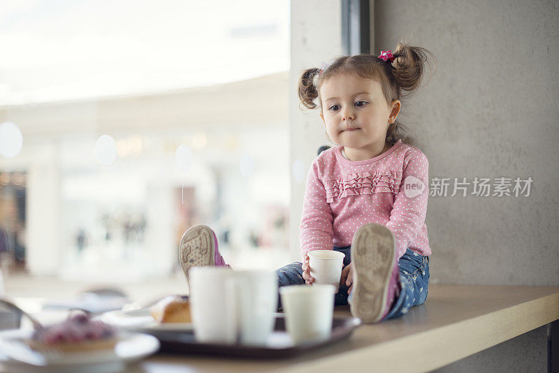 蹒跚学步的小女孩在咖啡厅喝热巧克力