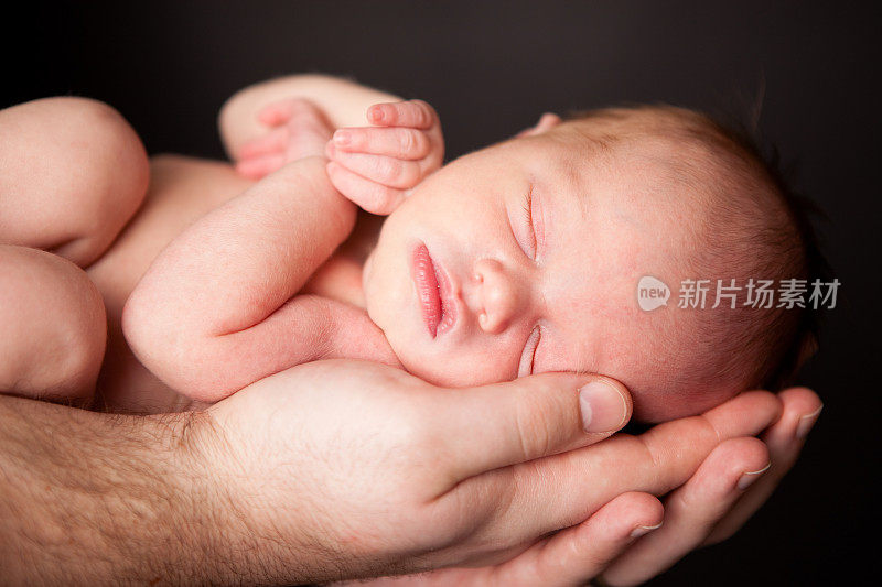 一位父亲的手抱着他刚出生的婴儿